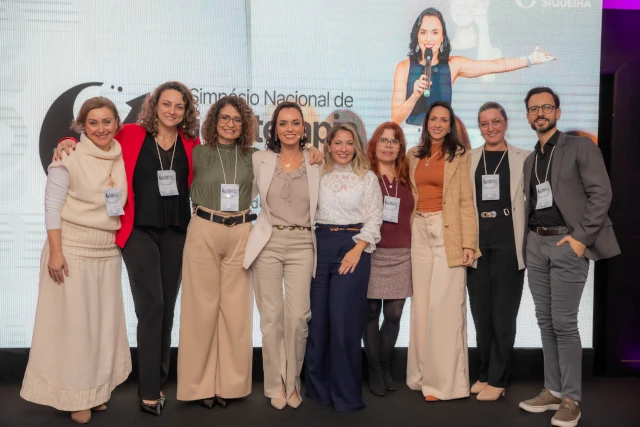 Palestrantes posando juntos para foto no palco